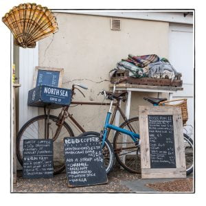 Image of a beachside stall in Norfolk, UK, framed with a sketch line and overlaid with a hand drawn image of a shell