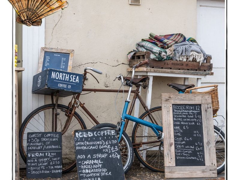 Image of a beachside stall in Norfolk, UK, framed with a sketch line and overlaid with a hand drawn image of a shell