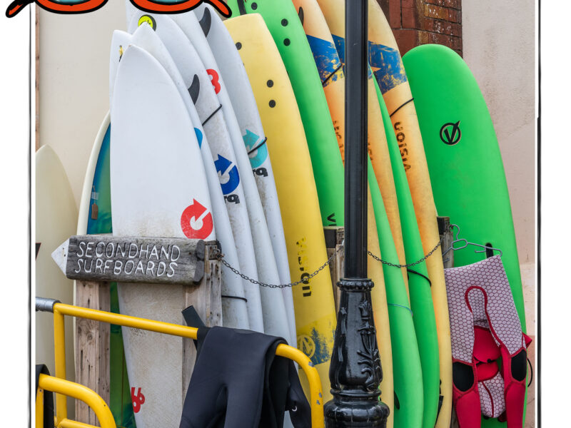 Image of a rack of surfboards near the beach in Norfolk, UK, framed with a sketch line and overlaid with a hand drawn image of sunglasses